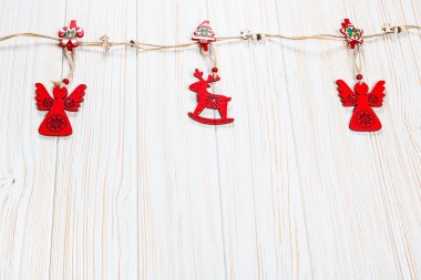 Noel bir geyik ve Beyaz ahşap zemin üzerinde bir melek ip şeklinde ahşap kırmızı oyuncaklar. Güzel bayram tebrik kartı boş alan ile
