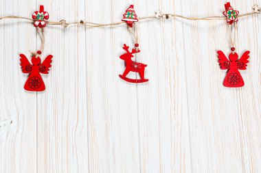 Noel bir geyik ve Beyaz ahşap zemin üzerinde bir melek ip şeklinde ahşap kırmızı oyuncaklar. Güzel bayram tebrik kartı boş alan ile