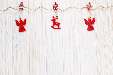Noel bir geyik ve Beyaz ahşap zemin üzerinde bir melek ip şeklinde ahşap kırmızı oyuncaklar. Güzel bayram tebrik kartı boş alan ile