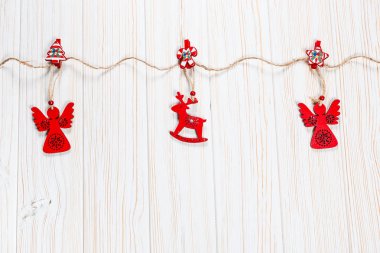 Noel bir geyik ve Beyaz ahşap zemin üzerinde bir melek ip şeklinde ahşap kırmızı oyuncaklar. Güzel bayram tebrik kartı boş alan ile