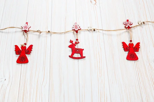Noel bir geyik ve Beyaz ahşap zemin üzerinde bir melek ip şeklinde ahşap kırmızı oyuncaklar. Güzel bayram tebrik kartı boş alan ile