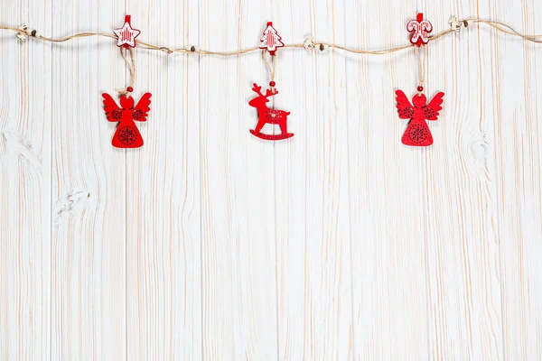 Natal brinquedos vermelhos de madeira na forma de um veado e uma corda angelical em um fundo de madeira branco. Belo cartão festivo com espaço livre — Fotografia de Stock