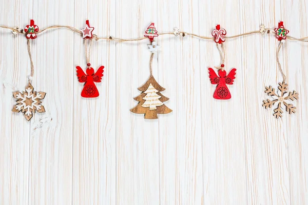 Os brinquedos de madeira de Natal penduram-se em uma corda em um contexto de madeira branco. Belo cartão festivo com espaço livre — Fotografia de Stock