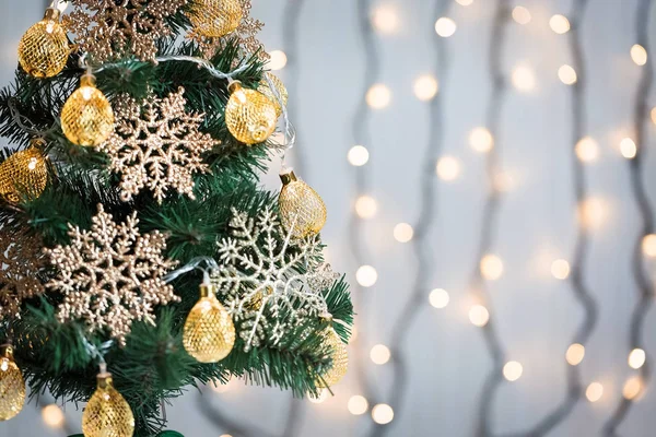 Un sapin de Noël décoré de flocons de neige et d'une guirlande sur le fond d'un bokeh et de planches blanches. Joyeux Noël, idées de cartes postales pour les vacances d'hiver — Photo