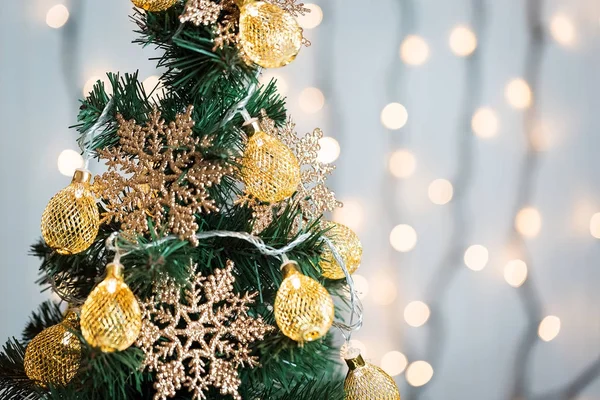 Un sapin de Noël décoré de flocons de neige et d'une guirlande sur le fond d'un bokeh et de planches blanches. Joyeux Noël, idées de cartes postales pour les vacances d'hiver — Photo