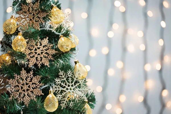 Un sapin de Noël décoré de flocons de neige et d'une guirlande sur le fond d'un bokeh et de planches blanches. Joyeux Noël, idées de cartes postales pour les vacances d'hiver — Photo