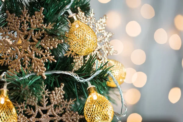 Un árbol de Navidad decorado con copos de nieve y una guirnalda en el fondo de un bokeh y pizarras blancas. Feliz Navidad, ideas para postales para vacaciones de invierno —  Fotos de Stock