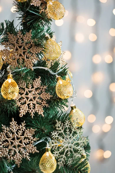 Un sapin de Noël décoré de flocons de neige et d'une guirlande sur le fond d'un bokeh et de planches blanches. Joyeux Noël, idées de cartes postales pour les vacances d'hiver — Photo