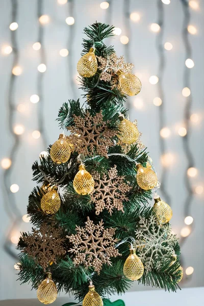 Een kerstboom versierd met sneeuwvlokken en een slinger op de achtergrond van een bokeh en witte platen. Vrolijke Kerstmis, ideeën voor ansichtkaarten voor wintervakantie — Stockfoto