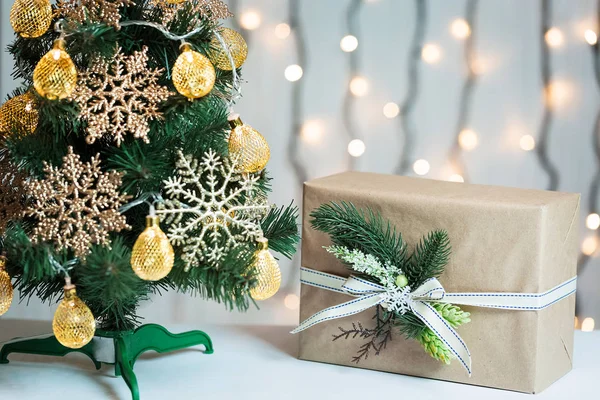 Un sapin de Noël décorait des flocons de neige et une guirlande avec une boîte cadeau sur le fond d'un bokeh et des tableaux blancs. Joyeux Noël, idées de cartes postales pour les vacances d'hiver — Photo