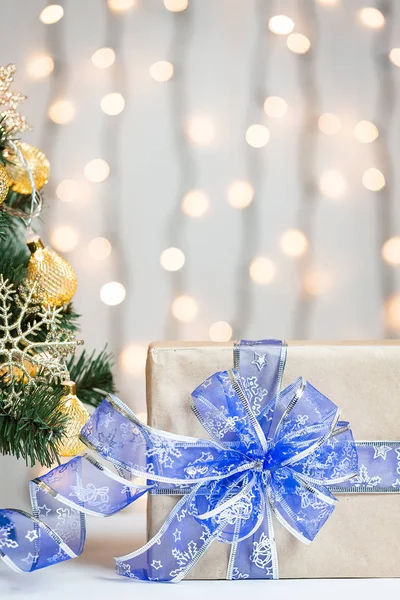 Un árbol de Navidad decorado con copos de nieve y una guirnalda con caja de regalo en el fondo de un bokeh y pizarras blancas. Feliz Navidad, ideas para postales para vacaciones de invierno — Foto de Stock