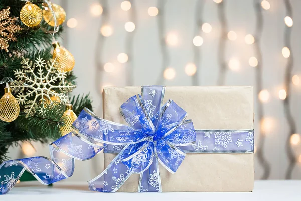 Un sapin de Noël décorait des flocons de neige et une guirlande avec une boîte cadeau sur le fond d'un bokeh et des tableaux blancs. Joyeux Noël, idées de cartes postales pour les vacances d'hiver — Photo