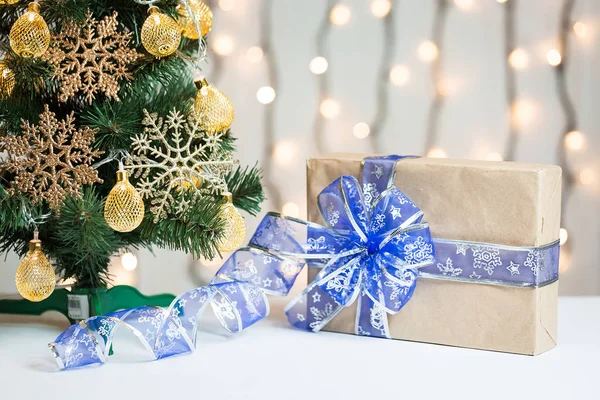 Een kerstboom ingericht sneeuwvlokken en een krans met de doos van de gift op de achtergrond van een bokeh en white boards. Vrolijke Kerstmis, ideeën voor ansichtkaarten voor wintervakantie — Stockfoto