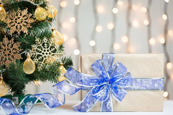 A Christmas tree decorated snowflakes and a garland with gift box on the background of a bokeh and white boards. Merry Christmas, ideas for postcards for winter holidays — Stock Photo, Image