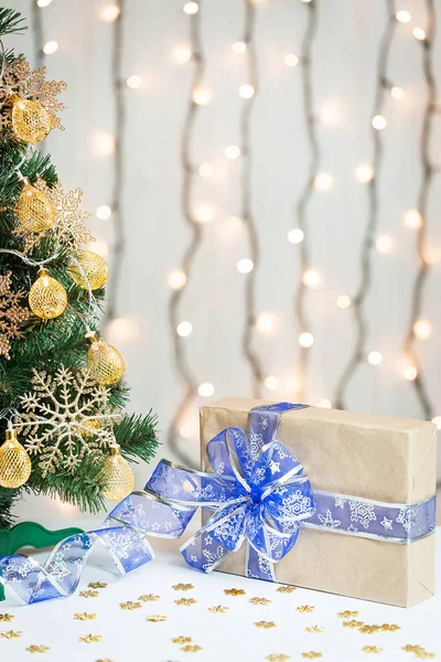 Un árbol de Navidad decorado con copos de nieve y una guirnalda con caja de regalo en el fondo de un bokeh y pizarras blancas. Feliz Navidad, ideas para postales para vacaciones de invierno — Foto de Stock