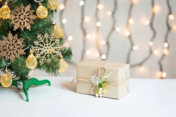 Un árbol de Navidad decorado con copos de nieve y una guirnalda con caja de regalo en el fondo de un bokeh y pizarras blancas. Feliz Navidad, ideas para postales para vacaciones de invierno —  Fotos de Stock