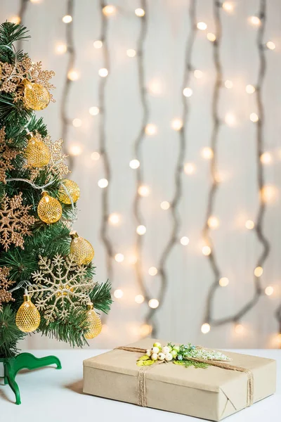 Un árbol de Navidad decorado con copos de nieve y una guirnalda con caja de regalo en el fondo de un bokeh y pizarras blancas. Feliz Navidad, ideas para postales para vacaciones de invierno —  Fotos de Stock
