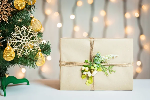 A Christmas tree decorated snowflakes and a garland with gift box on the background of a bokeh and white boards. Merry Christmas, ideas for postcards for winter holidays — Stock Photo, Image