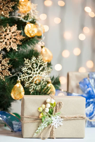 A Christmas tree decorated snowflakes and a garland with gift box on the background of a bokeh and white boards. Merry Christmas, ideas for postcards for winter holidays — Stock Photo, Image