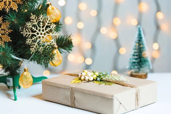 Un sapin de Noël décorait des flocons de neige et une guirlande avec une boîte cadeau sur le fond d'un bokeh et des tableaux blancs. Joyeux Noël, idées de cartes postales pour les vacances d'hiver — Photo