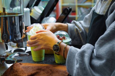 Kahve dükkanında çalışan barista. Eller kapağı kapatıyor. Kızlar az önce soğuk kibrit çayı yaptı. Yeşil kibrit ve beyaz krema