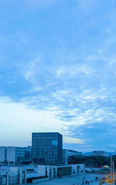 Batan güneşin altındaki şehir manzarası. Akşam güneş battıktan sonra gökyüzü bulutlarla kaplıydı. Şehrin mimari caddeleri ve gökyüzü tamamen birbirine uyuyor.