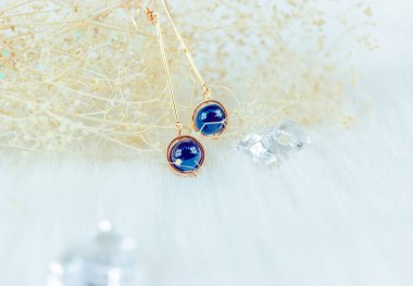 Bu bizim el yapımı küpemiz. Mavi yuvarlak boncuklar, safir taşına benzer taşlar, güzel bir doku. Solmuş bitkiler ve şeffaf buz küpleri fotoğrafçılık için iyi dekorasyonlardır. Beyaz peluş battaniye.