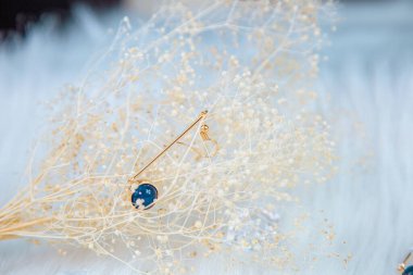 Bu bizim el yapımı küpemiz. Mavi yuvarlak boncuklar, safir taşına benzer taşlar, güzel bir doku. Solmuş bitkiler ve şeffaf buz küpleri fotoğrafçılık için iyi dekorasyonlardır. Beyaz peluş battaniye.