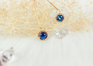 Bu bizim el yapımı küpemiz. Mavi yuvarlak boncuklar, safir taşına benzer taşlar, güzel bir doku. Solmuş bitkiler ve şeffaf buz küpleri fotoğrafçılık için iyi dekorasyonlardır. Beyaz peluş battaniye.