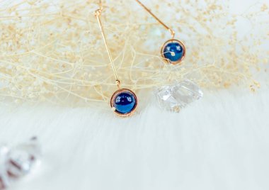 Bu bizim el yapımı küpemiz. Mavi yuvarlak boncuklar, safir taşına benzer taşlar, güzel bir doku. Solmuş bitkiler ve şeffaf buz küpleri fotoğrafçılık için iyi dekorasyonlardır. Beyaz peluş battaniye.