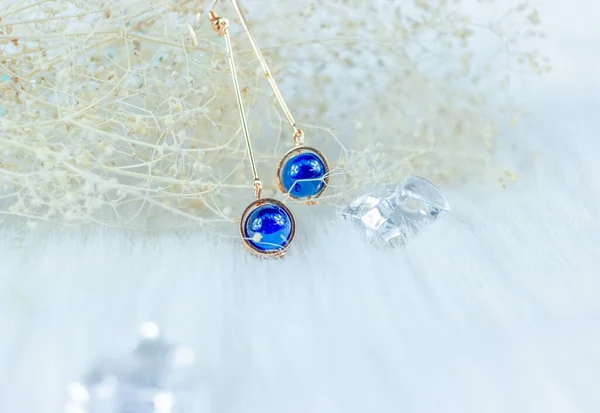 这是我们自己手工制作的耳环 蓝色圆形珠子 石头类似蓝宝石 质地优美 枯萎的植物和透明的冰块是很好的摄影装饰 白色毛毯 — 图库照片
