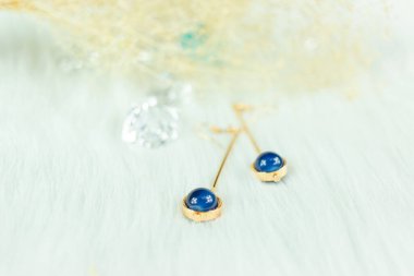 Mavi boncuk küpeler, metalden yapılmış el yapımı ürünler. Mavi yuvarlak boncuklar ve altın sarısı metalden yapılmış. Battaniyeler ve güzel kurumuş çiçekler süs olarak kullanılır. Şeffaf buz kalıpları.