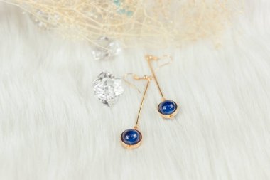 Mavi metal küpeler, solmuş bitkiler ve şeffaf buz küpeleri fotoğrafçılık için iyi dekorasyonlardır. Beyaz peluş battaniye. Mavi yuvarlak boncuklar ve altın sarısı metalden yapılmış.. 