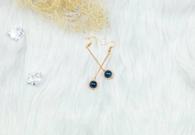  Mavi metal küpelerden yapılmış. Mavi yuvarlak boncuklar ve altın sarısı metalden yapılmış. Solmuş bitkiler ve şeffaf buz küpleri fotoğrafçılık için iyi dekorasyonlardır. Beyaz peluş battaniye.