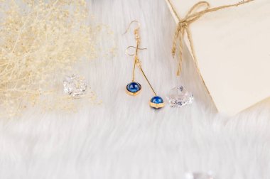 Bu bizim el yapımı küpemiz. Mavi yuvarlak boncuklar, safir taşına benzer taşlar, güzel bir doku. Battaniyeler ve güzel kurumuş çiçekler süs olarak kullanılır. Şeffaf buz kalıpları.