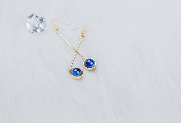 Made of blue round beads and golden yellow metal.  Down blankets and beautiful dried flowers are used as decorations.  Close-up of blue metal earrings.Made of blue round beads and golden yellow metal.Transparent ice cube props.