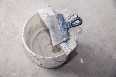 İnşaat kovasında dekoratif çimento sıva ve mala sıva için hazır. Spatula ve bir kova beyaz macun. Üst görünüm