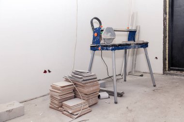 Profesyonel bir alet. Banyoda fayans kesici ve fayans yığını var. Beyaz alçılı duvarlar. Dairelerde konsept onarımı, döşeme döşemeleri, içeride onarım.