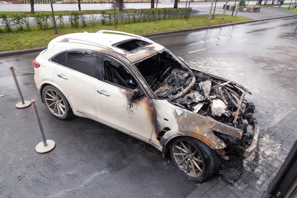 Kemerovo 2019-09-16 Carro branco Infiniti FX50S queimado, estacionado ao ar livre perto do edifício, janelas fumadas rachadas de fogo. Capuz cortado, pára-choques, sem pára-brisas, curto-circuito de fiação — Fotografia de Stock