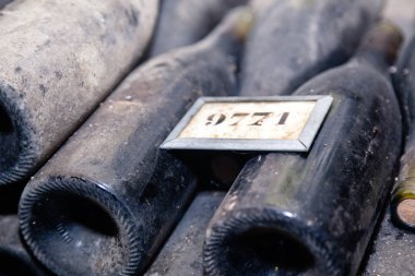 Eski siyah tozlu şarap şişeleri yeraltı mahzeninde yaşlanıyor.