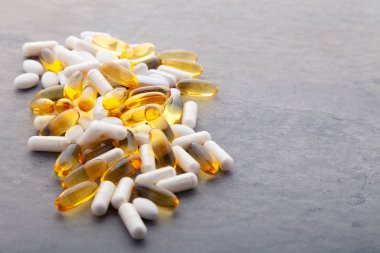 Tabletler, haplar, kapsüller, beyaz arka planda beyaz şişeden akan uyuşturucular. Spor, sağlıklı yaşam tarzı, ilaç, beslenme malzemeleri, insan konsepti - kapanış balık yağı kapsülleri yumuşak jel