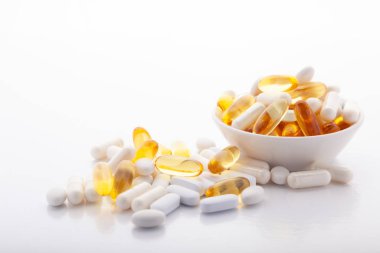 Çeşitli ilaçlar ilaç vitaminleri, haplar, gri arka planda kasede uyuşturucular. Beyaz gıda besin takviyesi sert kabuklu kapsüller toz, somon yağı softgel Omega 3