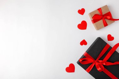 Kırmızı kurdeleli siyah hediye kutusu ve beyaz arka planda kalpleri olan şenlikli kraft. Kadınlar Sevgililer Günü, yıldönümü, anneler günü, doğum günü telif hakkı, üst görünüm