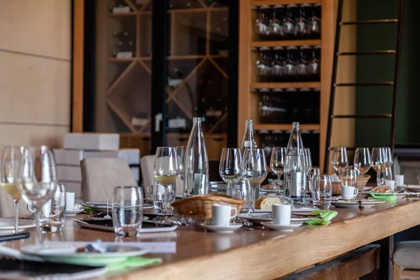 Närbild tom transparent kristall vin och glas vatten, flaskor, bröd, kaffe, tekoppar på bordet. Begreppet modern inställning på professionell degustation, middag i vingård på vinhyllor bakgrund — Stockfoto