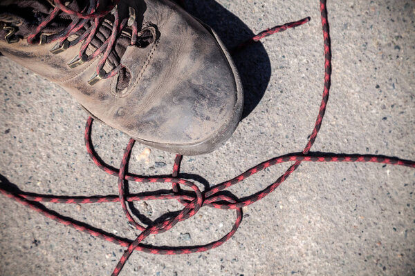 Pair of favorite, worn and dirty high-altitude trekking boots covered in mud and shoelaces, top view. Concept travel, hiking, walking in mountains.