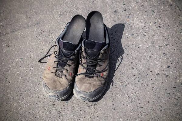 泥や靴ひもで覆われたお気に入りの、着用され、汚れた高高度のトレッキングブーツのペアは、トップビュー。コンセプト旅行、ハイキング、山の中を歩く. — ストック写真