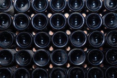 Mahzende, bodrumda, şarap deposunda, şaraphanede sıralanmış eski, tozlu şarap şişelerinin diplerindeki yakın çekim kalıpları. Eski nadir şaraplarla dolu kasa dairesi, nadir bulunan bir şişe koleksiyonu. Mozaik arkaplan