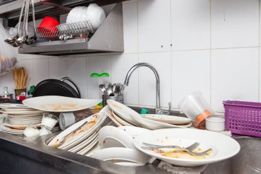 Kirli bulaşık, çanak çömlek, sofra takımı dolu bir metal lavabo.