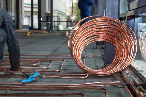 Fontanero colocando tubos de cobre en el suelo con calefacción caliente — Foto de Stock