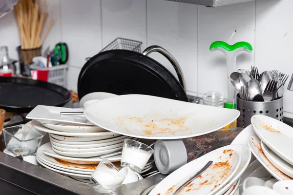 Metal sink full of dirty dishes, crockery, tableware